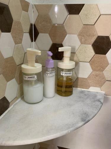 three bottles of essential oils on a shelf in a bathroom at De Suria Homestay Jitra in Jitra