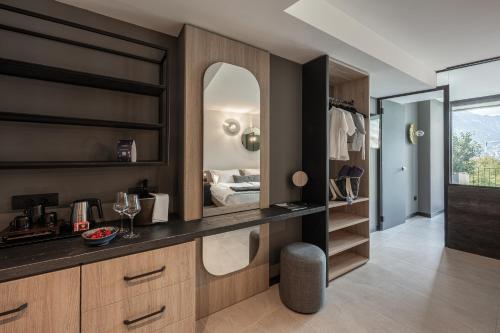 a bathroom with a vanity with a mirror and a bedroom at Gardea SoulFamily Resort in Nago-Torbole