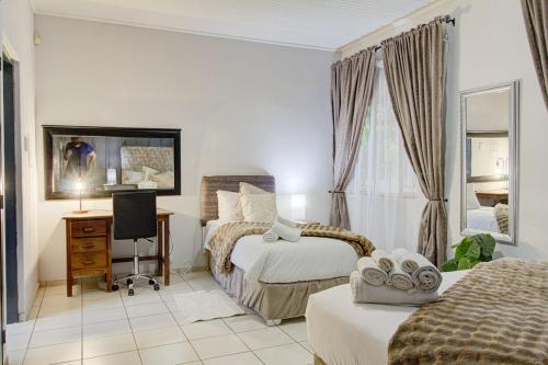 a bedroom with two beds and a desk and a television at Spacious Valkyrie One-bedroom in Centurion