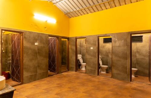 een badkamer met 3 toiletten en een gele muur bij Dandeli Heritage Resort in Dandeli