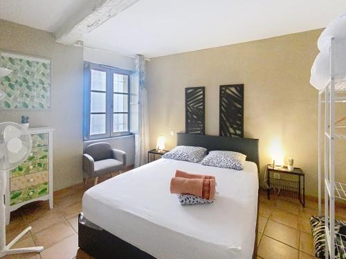 a bedroom with a large white bed and a chair at Le Gaveau superbe T3 médiéval Internet WiFi gratuit Arènes historiques in Béziers