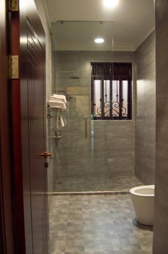 a bathroom with a shower and a toilet and a window at Bellwether Apartments in Kampala