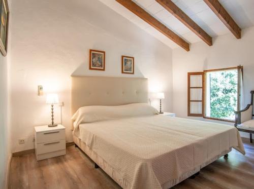 a white bedroom with a bed and a window at Can Gat in Pollença