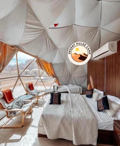 a bedroom with a tent with a bed and chairs at RUM BULSE BUBBLE lUXURY CAMP in Wadi Rum