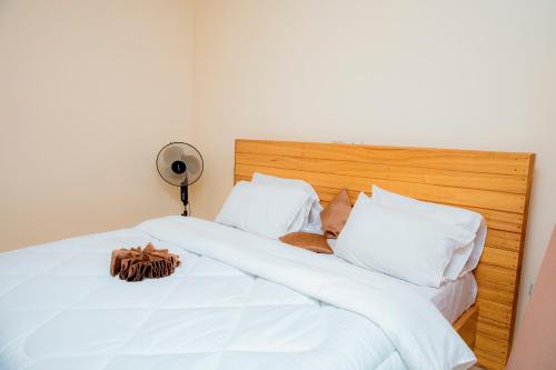 Una cama con sábanas blancas y almohadas con sombrero. en THELIGHT SUITES KIGALI Rwanda, en Kigali