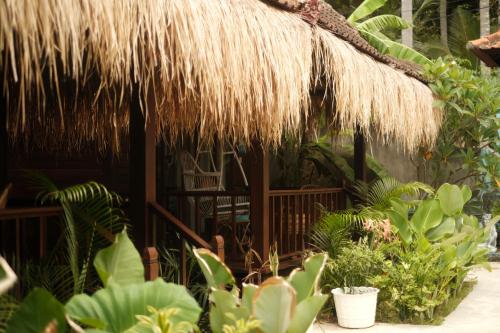 une cabane avec un toit de paille et quelques plantes dans l'établissement Alinn Villas, à Nusa Lembongan