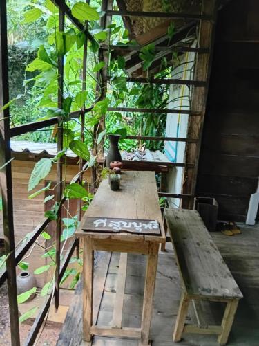 a wooden table with a vase sitting on top of it at hug pang mao homestay Lampang โฮมสเตย์ฮักปางมะโอ ลำปาง in Ban Cham Pu Loei