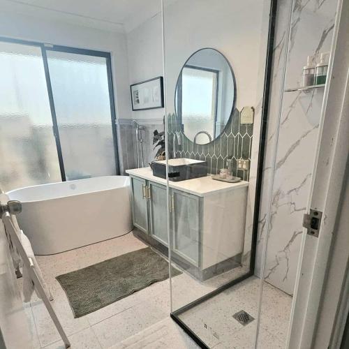 a bathroom with a tub and a sink and a mirror at Joyful living Home Stay in Coogee