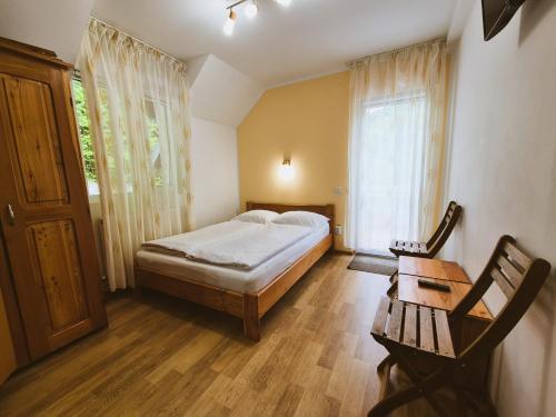 Un dormitorio con una cama y una mesa y una ventana. en Casa Sonne, en Buşteni