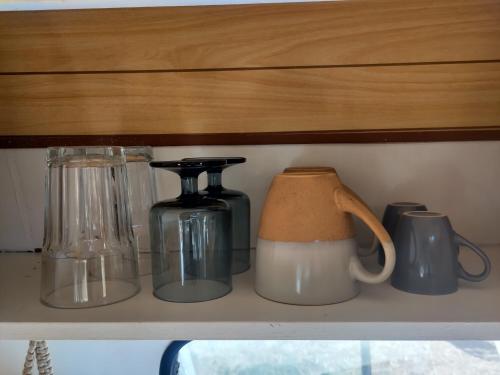 a shelf with jars and coffee makers on it at Cosy nest in animal rescue Monte dos Vagabundos in São Teotónio
