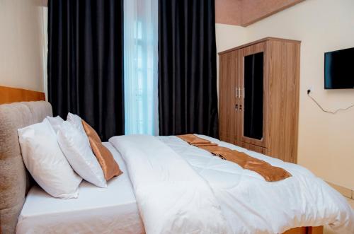 a bedroom with a bed with white sheets and pillows at THELIGHT SUITES KIGALI Rwanda in Kigali