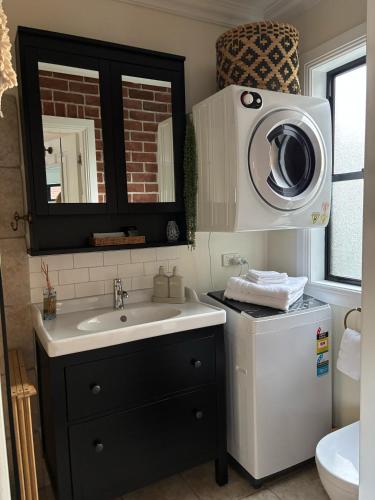 a bathroom with a sink and a washing machine at The Bungalow - Luxurious & Calm - Beach and Bush Retreat in Valla Beach
