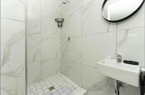 a white bathroom with a sink and a mirror at Ava Guest House in Johannesburg