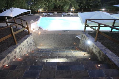 a swimming pool with a table and umbrellas next to it at Tenuta Terre di Bosco Oasi di Relax nel Cilento in San Giovanni a Piro