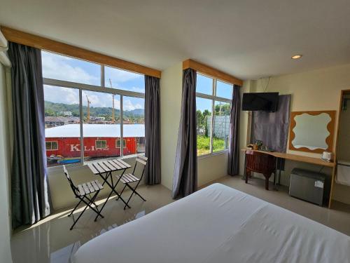 a bedroom with a large bed and a table and chairs at Dwell Phuket Airport Hotel at Naiyang in Nai Yang Beach