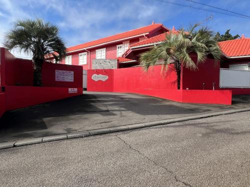 a red building with palm trees next to a street at Mariage Hotel - Adults Only - in Tsukuba