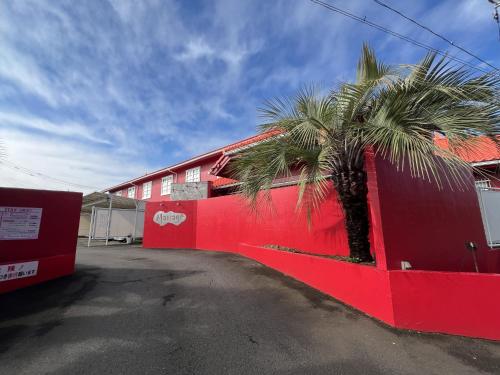a red building with a palm tree next to it at Hotel Mariage Tsukuba in Tsukuba