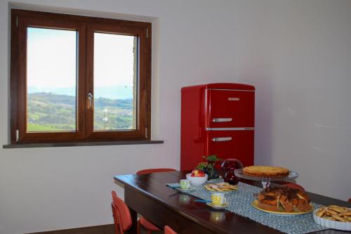 cocina con mesa con comida y nevera roja en Casetta Mentuccia, en San Ginesio