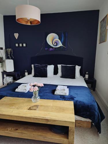 a blue bedroom with a bed with a wooden table at Super king bedroom with large ensuite in Brighton & Hove