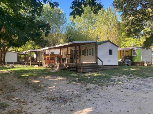 ein kleines Haus in einem Hof mit Bäumen im Hintergrund in der Unterkunft Mobilhome 3 chambres in Mialet
