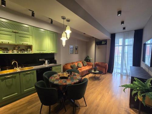 cocina y sala de estar con armarios verdes y mesa en Green House Mindeli, en Tiflis