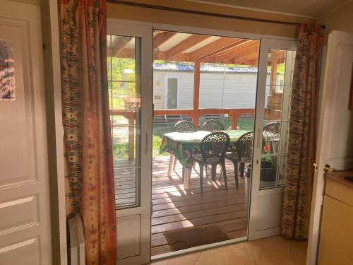 eine offene Tür zu einer Terrasse mit Tisch und Stühlen in der Unterkunft Mobilhome 3 chambres in Mialet