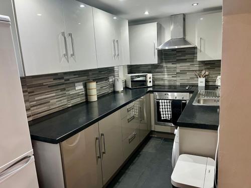 a kitchen with white cabinets and black counter tops at New 3 Bed Preston City Centre No Parking- Sleeps 8 in Preston