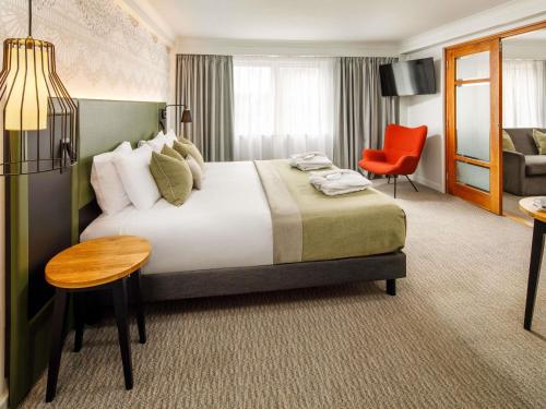 a hotel room with a large bed and a red chair at Mercure Nottingham Sherwood in Nottingham