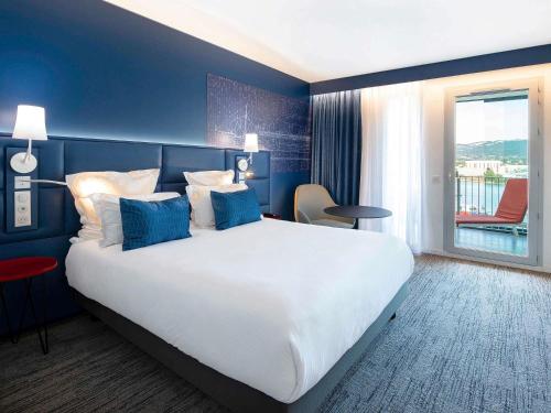 a hotel room with a large bed with blue walls at Hôtel Mercure Toulon La Seyne-Sur-Mer in La Seyne-sur-Mer