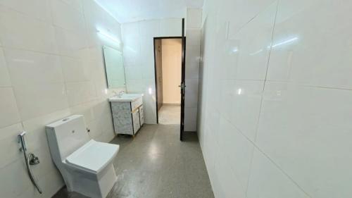 a white bathroom with a toilet and a sink at Shri Rudra's Service Apartments in Bhīm Tāl