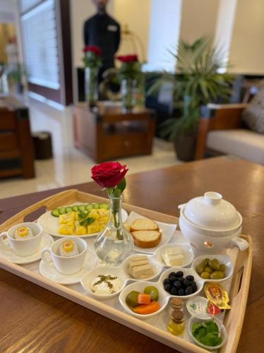 een dienblad met eten en een vaas met een roos erop bij شركة منازل التوت للشقق المخدومة جده in Jeddah