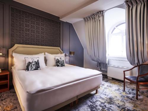 Un dormitorio con una cama y una ventana y una silla. en Mercure Sibiu Airport, en Sibiu