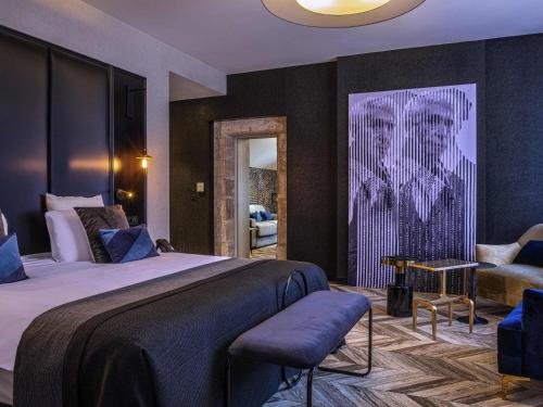 a bedroom with a king sized bed and a chair at Mercure Figeac Viguier du Roy in Figeac