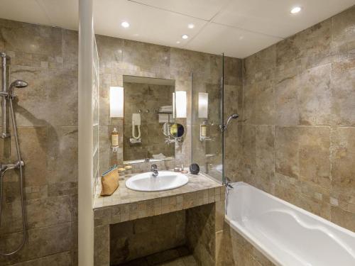 a bathroom with a sink and a tub at Mercure Marseille Centre Bompard La Corniche in Marseille