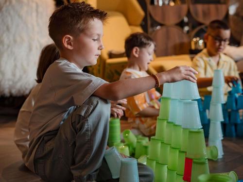 a young boy playing with a group of green plastic cups at Mercure Timisoara in Timişoara