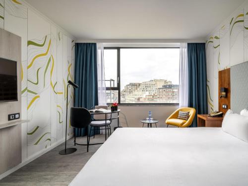 アントワープにあるMaek Hotel Antwerp Central - Handwritten Collectionのベッドとテーブルと窓のあるホテルの部屋