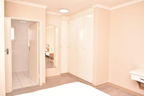 ein Badezimmer mit weißen Schränken und einem Spiegel in der Unterkunft holiday home away from home1 in Johannesburg