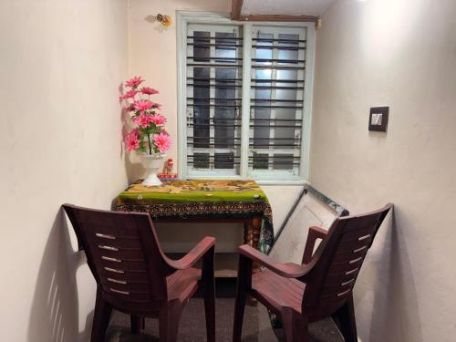 a table and two chairs in a room with a window at Swasthiks Home stay in Sakleshpur