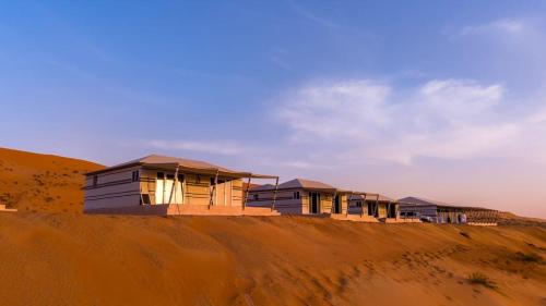 a row of houses on top of a sand hill at Desert Escape Camp Wahiba in Ibrā