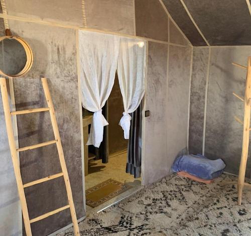 a room with a mirror and a ladder and a bed at Acacia Luxury Camp in Merzouga