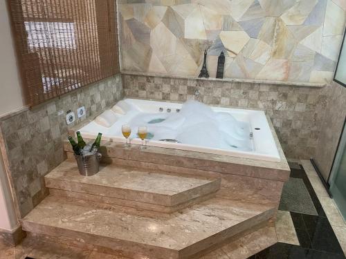eine große Badewanne mit zwei Weingläsern in der Unterkunft Belíssima Casa Stella Maris -Casa de Carrara3 in Andradina