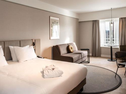 una habitación de hotel con una cama y una silla en Mercure Liege City Centre, en Lieja