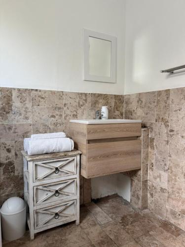 a bathroom with a sink and a wooden dresser at Windekind in Struisbaai