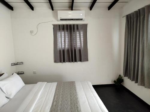 a bedroom with a white bed and a window at Step Inn Ahangama in Ahangama