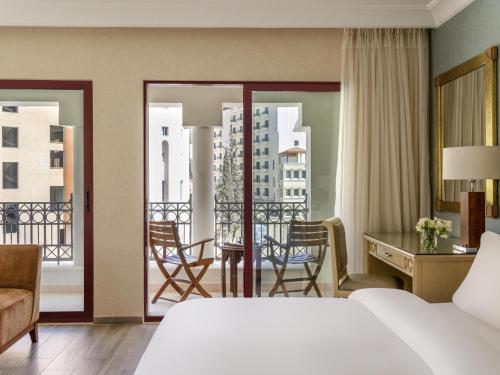 a hotel room with a bed and a desk and a balcony at Mövenpick Resort Petra in Wadi Musa