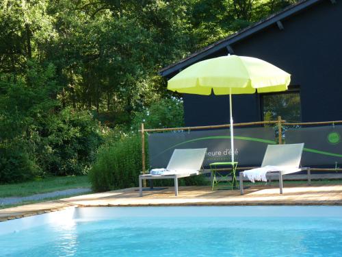 deux chaises et un parasol à côté d'une piscine dans l'établissement A l'Heure d'Eté, à Fargues-de-Langon