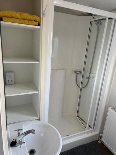 Un baño blanco con ducha y lavabo. en Beautiful Holiday Home Close to the Sea, en Poughill