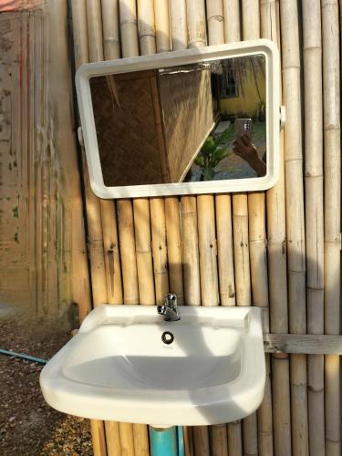 a bathroom sink with a mirror on a bamboo wall at Lanta Rabbit Rooms in Ko Lanta