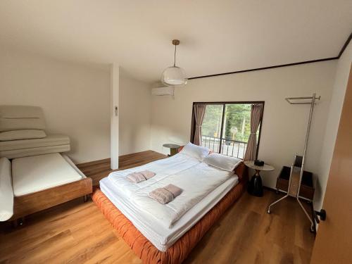 a bedroom with a large white bed with a window at 雲の家 旧東海道沿いの畑宿の温もりステイ in Hakone