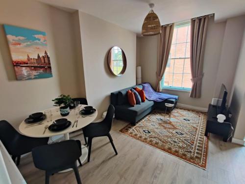 een woonkamer met een tafel en een bank bij Victoria's Bright Georgian Apartment in Liverpool